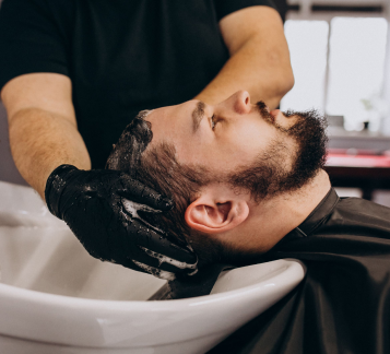 Cabeleireira lavando cabelo de cliente em uma barbearia